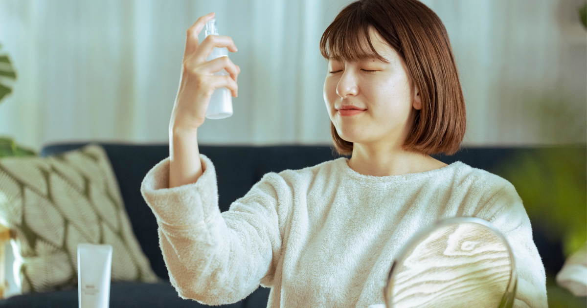 ミストを顔に振りかける女性