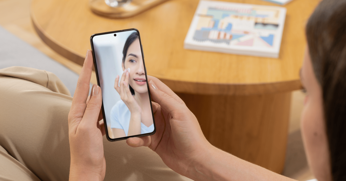 顔にクリームを塗っている女性が写っているスマホを見ている女性